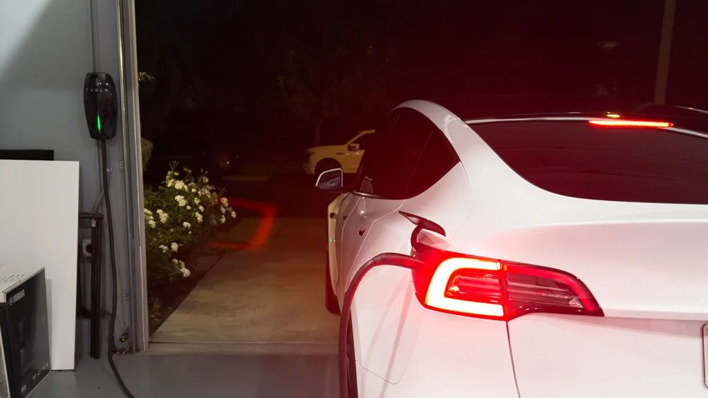 A Level 2 EV charger installed by American Electric Co on a garage wall, charging a Tesla overnight at home