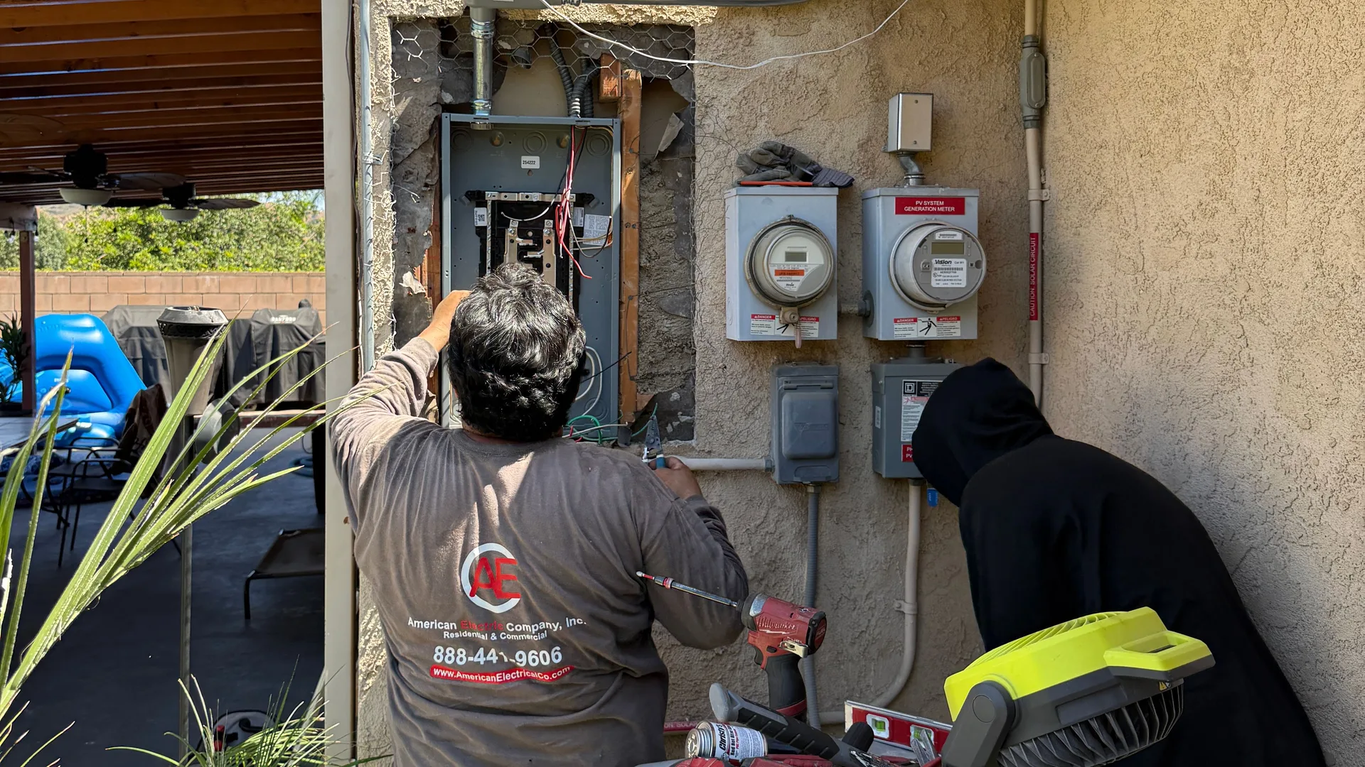 American Electric Co electricians installing a residential sub-panel beside the utility meter and solar generation meter